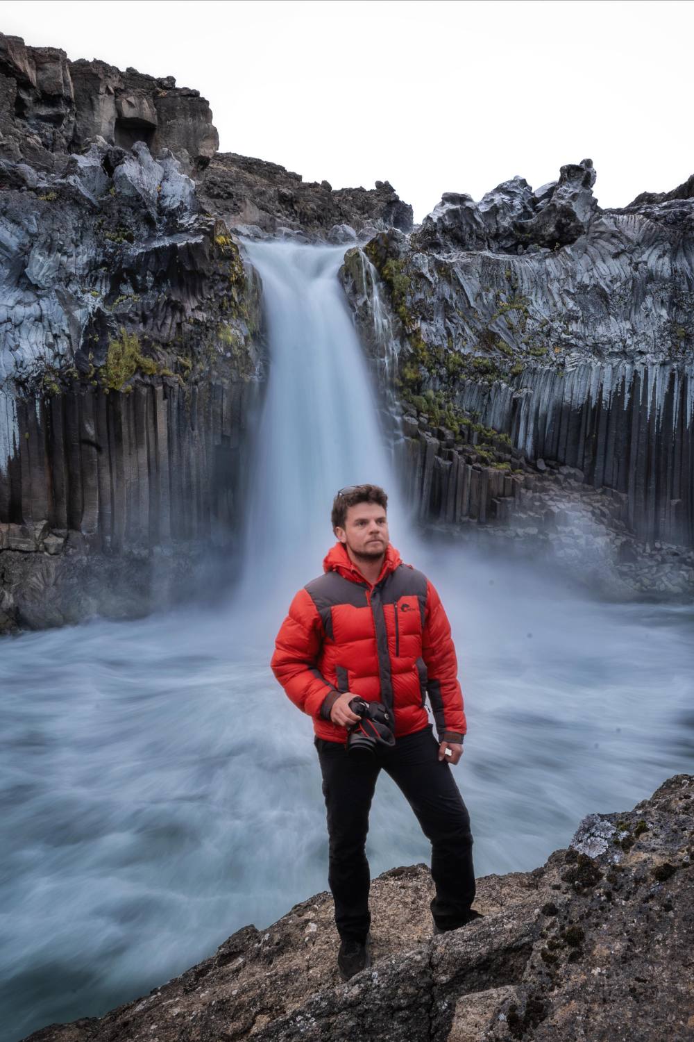 Erick con su cámara frente a una cascada en Europa